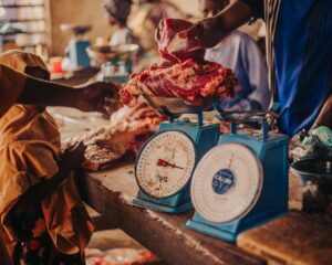 Fresh meat being weighed in a vibrant local market setting.